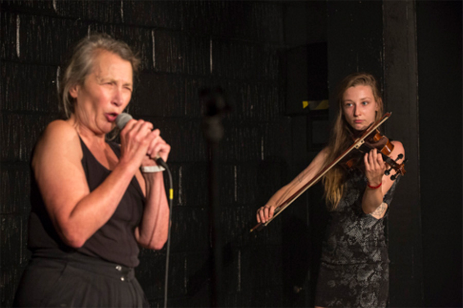 A singer performs with a violinist on stage, showcasing the artistry of Bollywood music.
